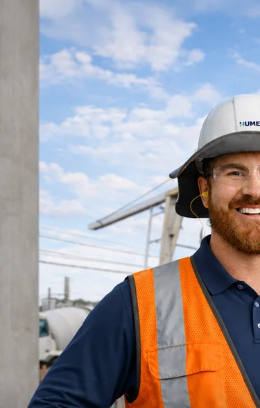 Cover of the Humes Capability Statement showing a smiling Humes worker in a hard hat and hi-vis vest at a precast yard with a gantry crane.